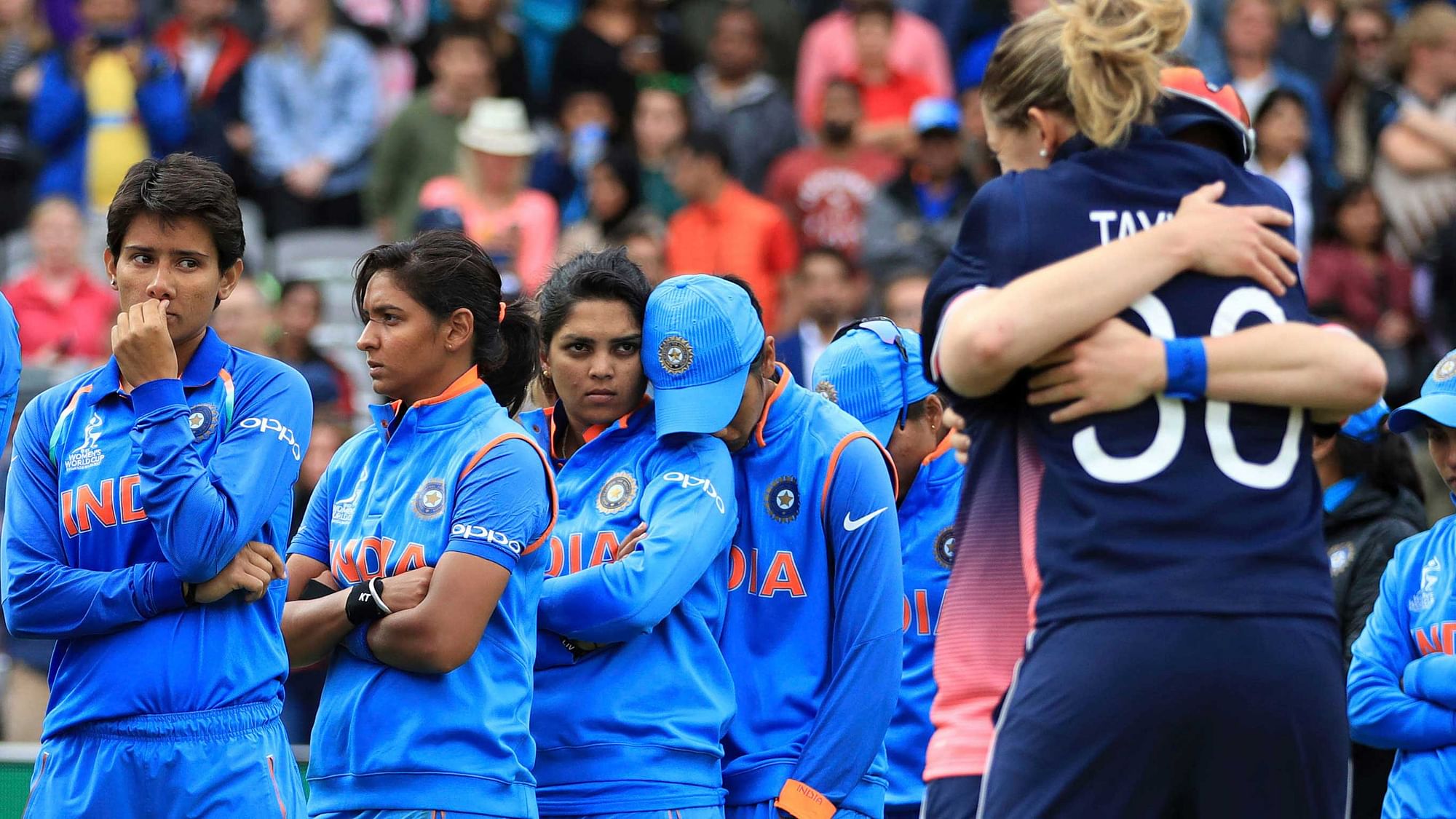 Indian women’s team watch on as English players celebrate their World Cup final victory.&nbsp;