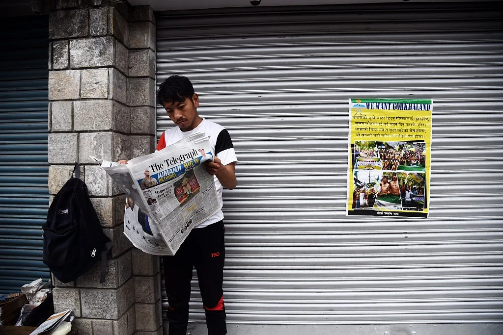 A lone man reads a newspaper.