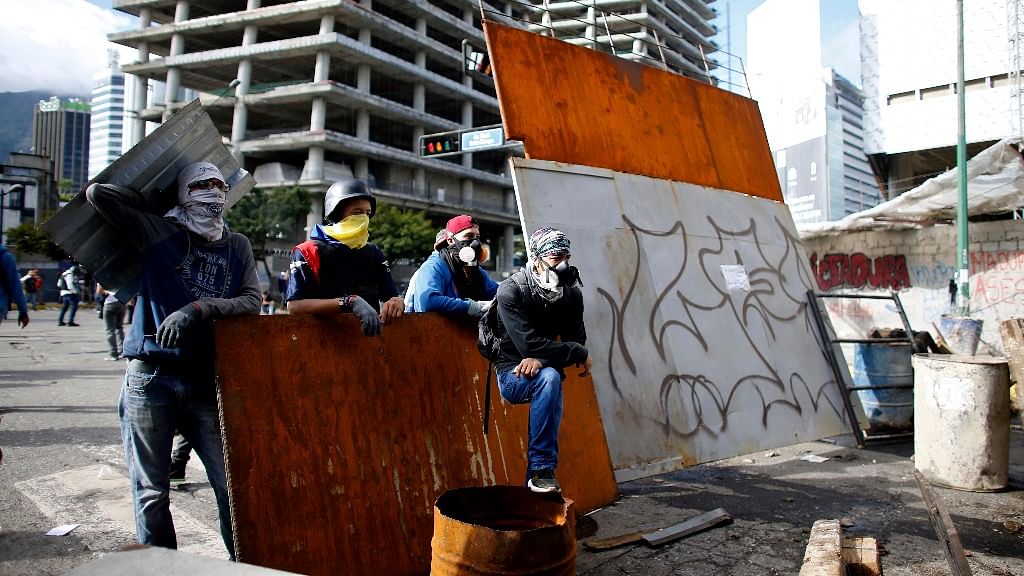

Anti-government demonstrators wait for Venezuelan Bolivarian National Guards, at a barricade in Caracas, Venezuela.