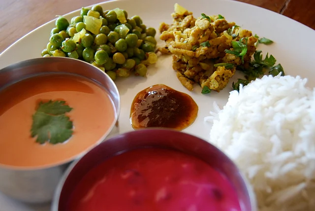 The marathi thali comprises santosh, beet raita, lemony green peas, tamarind chutney, ground chicken with cumin, and Basmati rice.