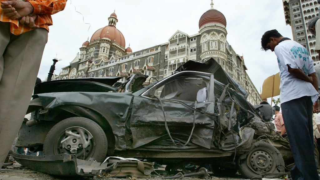 

People look at a car wrecked by the bomb blast outside Taj Hotel on 25 August  2003.