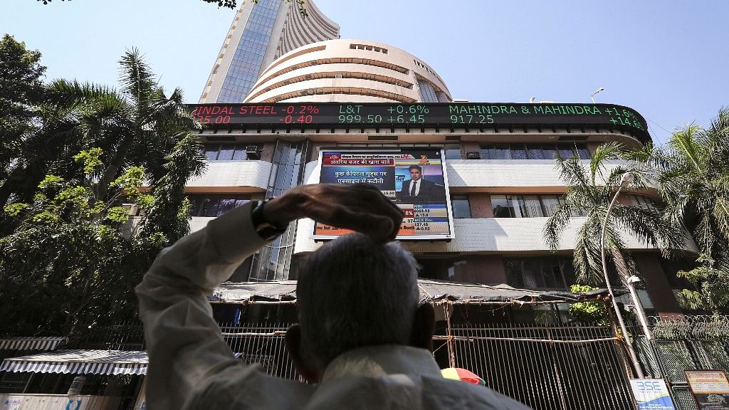 A man looks at a screen across the road displaying the Sensex on the facade of the Bombay Stock Exchange (BSE) building in Mumbai.