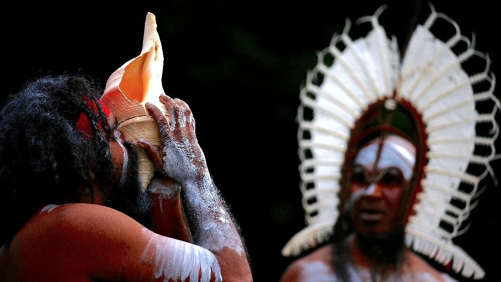 An Australian Aboriginal man blows into a shell while an indigenous man from the Torres Strait Islands wearing traditional dress performs during a welcoming ceremony at Government House in Sydney, Australia.