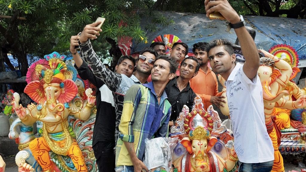 Young devotees take a selfie in front of a Ganesh idol.