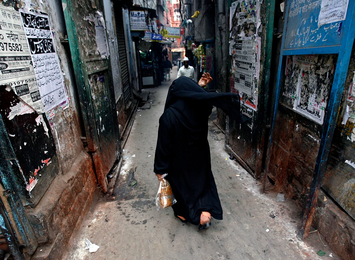 A veiled Muslim woman walks down a street. 
