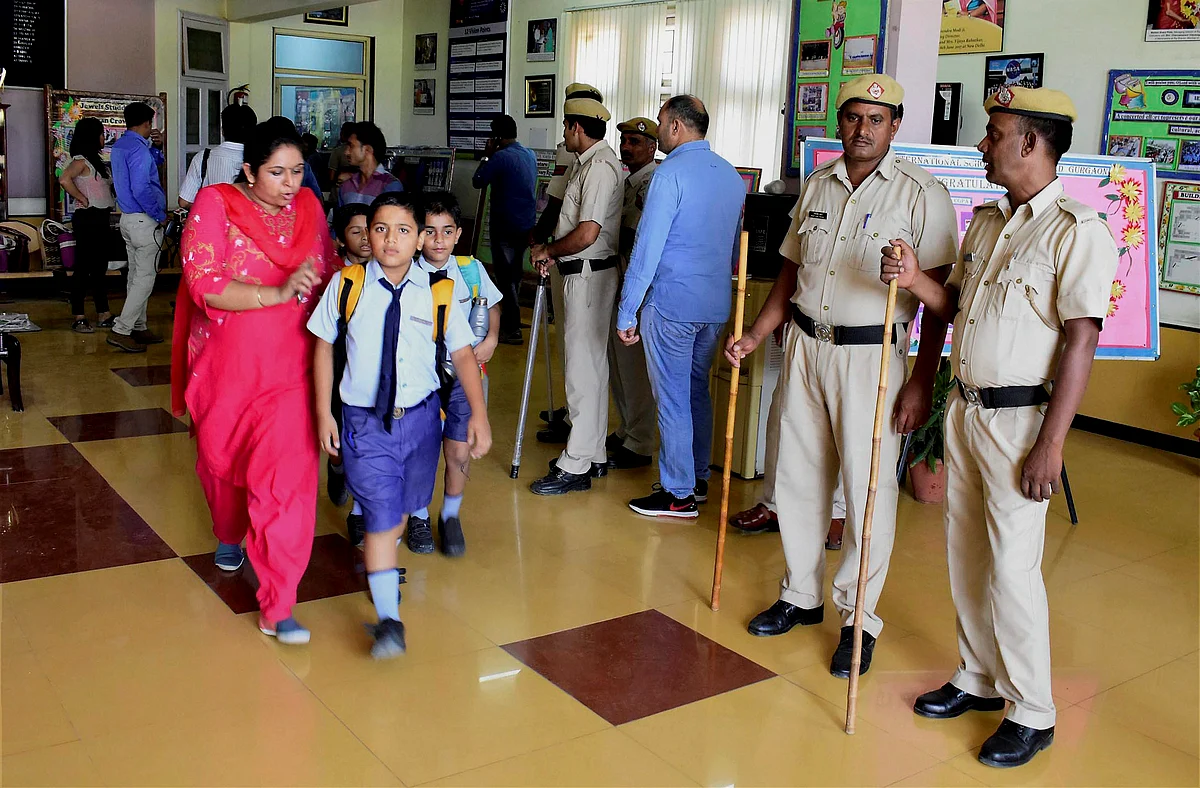 Parents take their children home after the murder of a class 2 student at Ryan International School as a police team looks on, in Gurugram on Friday.
