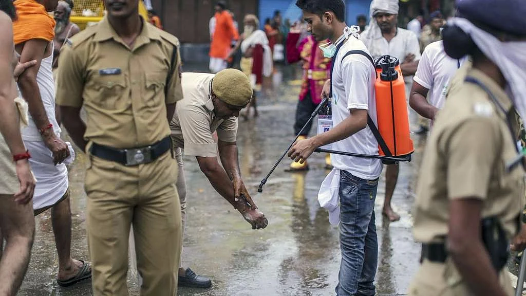 A street cleaner assists a police officer cleaning his hands in Nashik, Maharashtra, India.