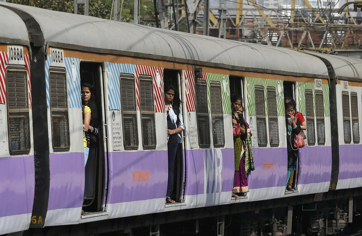 Commuters stand on the doors of a suburban train as it approaches the Churchgate railway station in Mumbai.