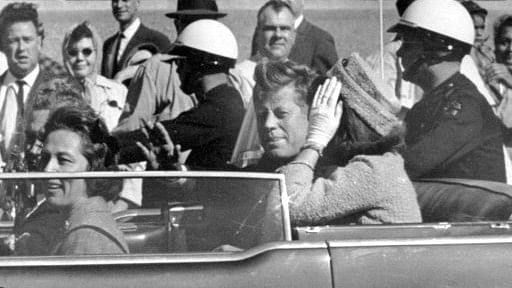 President John F Kennedy waves from his car in a motorcade approximately one minute before he was shot in Dallas.