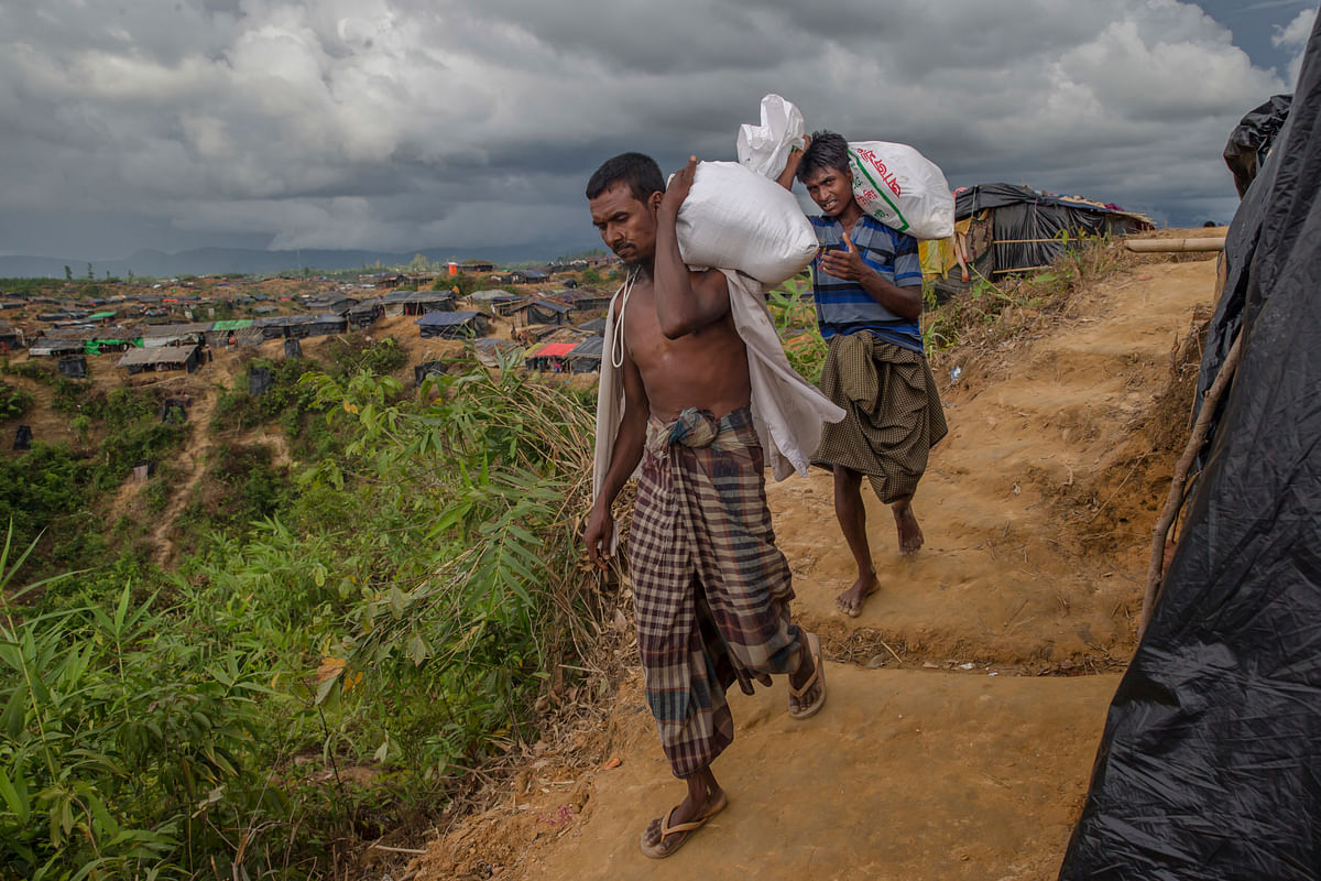  Rohingya Muslims who crossed over from Myanmar walk back to their shelters after collecting aid in Taiy Khali refugee camp, Bangladesh.