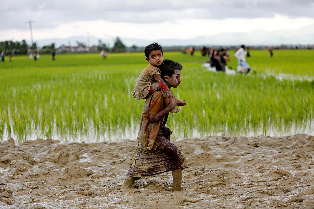 A young boy carries a child on his back after crossing the Myanmar-Bangladesh border.