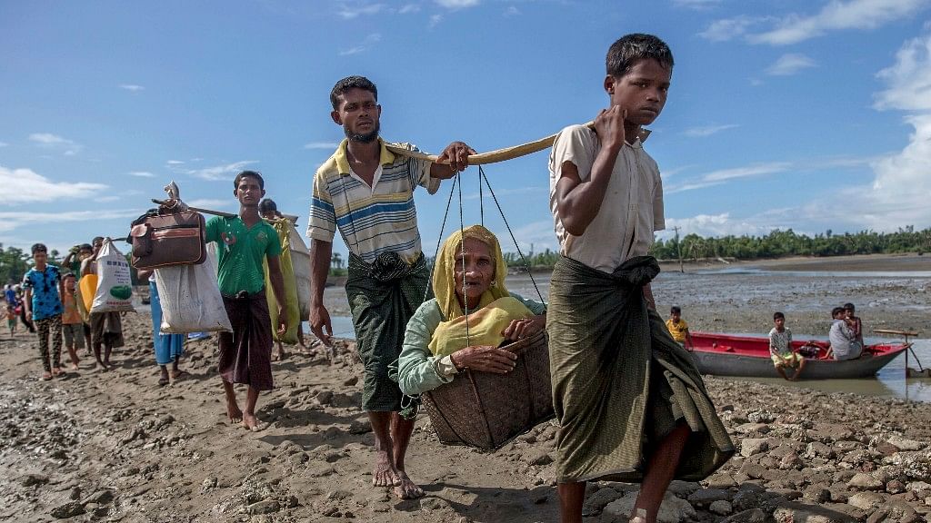  Rohingya Muslims, who crossed over from Myanmar into Bangladesh, carry an elderly woman in a basket and walk towards a refugee camp in Shah Porir Dwip, Bangladesh, 14 September 2017. 