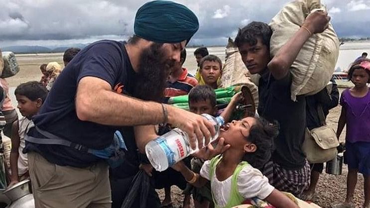 A Sikh volunteer at Teknaf, on the Bangladesh-Myanmar border, gives water to a Rohingya Muslim child.