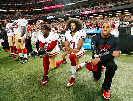 In this file photo, San Francisco 49ers quarterback Colin Kaepernick (7), who was the first to protest in such a way, kneels down along with outside linebacker Eli Harold (58) during the national anthem before a game against the Atlanta Falcons in Atlanta.