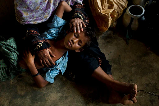 A Rohingya woman comforts her exhausted son as they take shelter inside a school after having just arrived from the Myanmar side of the border at Kutupalong refugee camp in Bangladesh.