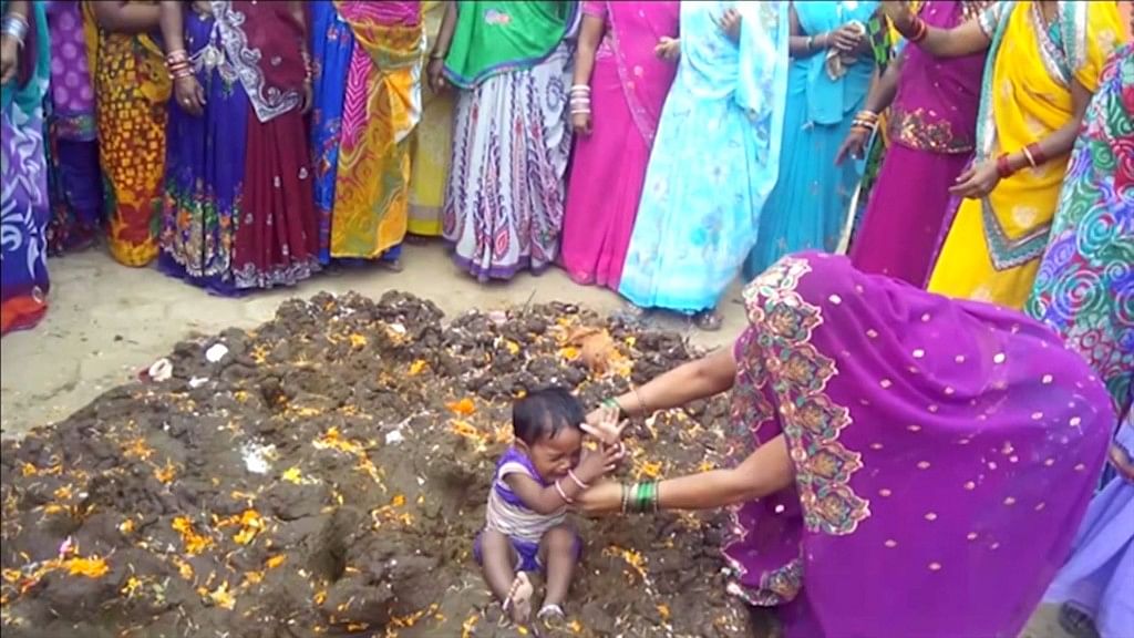 Parents rolling kids in cow dung