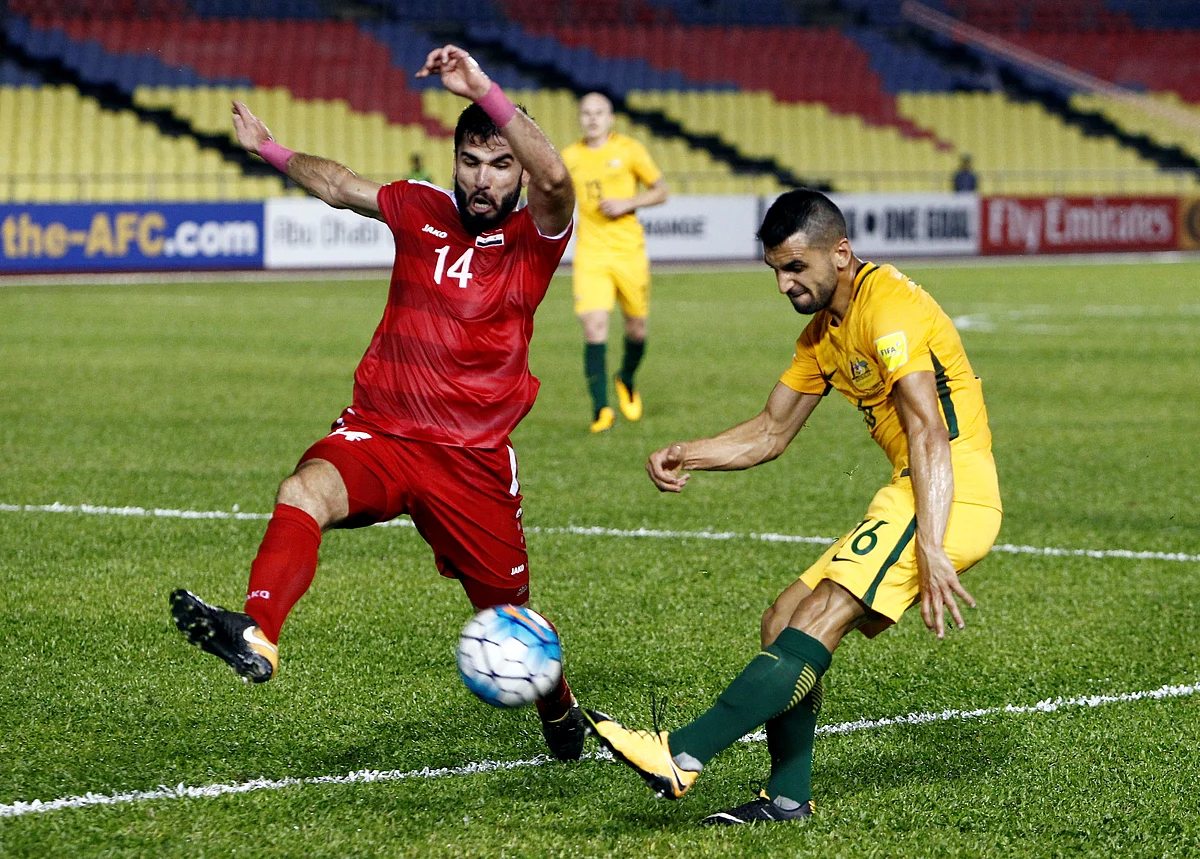 Syria’s Tamer Haj Mohamad challenges Australia’s Aziz Behich.