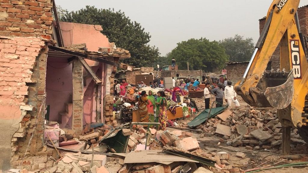 Settlers of Kathputli Colony wait where their homes once stood, minutes after they were demolished by the Delhi Development Authority bulldozers on Monday, 30 October.