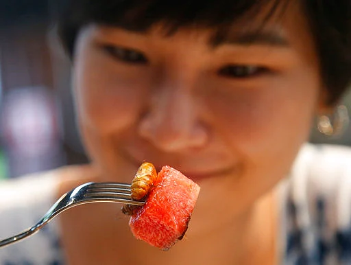 Amornrat Simapsaisan, a local shop manager, eats a watermelon salad with bamboo worms at Insects in the Backyard restaurant, in Bangkok, Thailand.