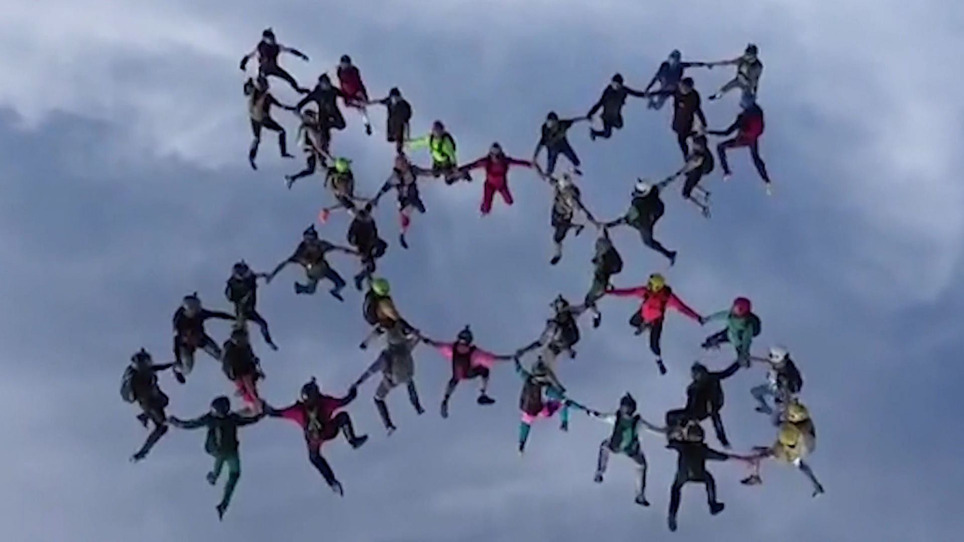 The skydivers form a human chain in the sky.