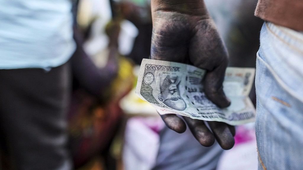A vendor holds an Indian one hundred rupee banknote at a market stall in Mumbai on 11 March  2017.&nbsp;