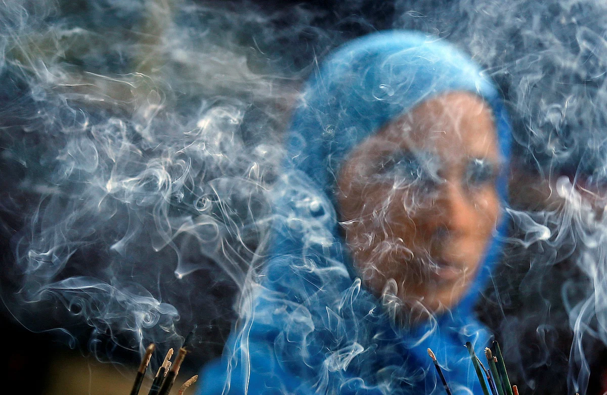 Smoke rises from burning incense sticks as a woman prays inside the shrine of Muslim Sufi Saint Nizamuddin Auliya in New Delhi.