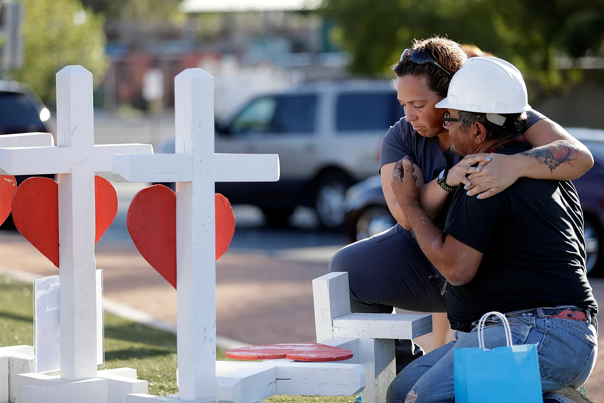 Ebony Saunders, left, hugs Greg Zanis in front of his memorial crosses, on 5 October, in Las Vegas.
