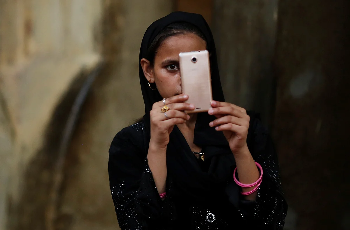 A Muslim girl takes picture with a mobile phone before having her Iftar (breaking of fast) meal during the holy month of Ramadan inside the shrine of Muslim Sufi Saint Nizamuddin Auliya in New Delhi.