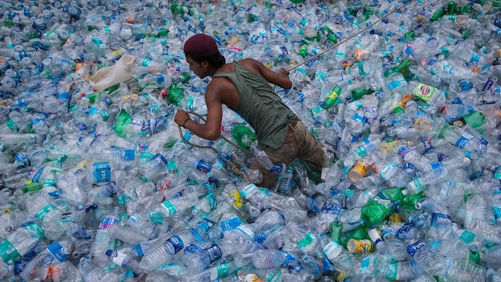 A worker  moves through a pile of empty plastic bottles at a recycling workshop.&nbsp;