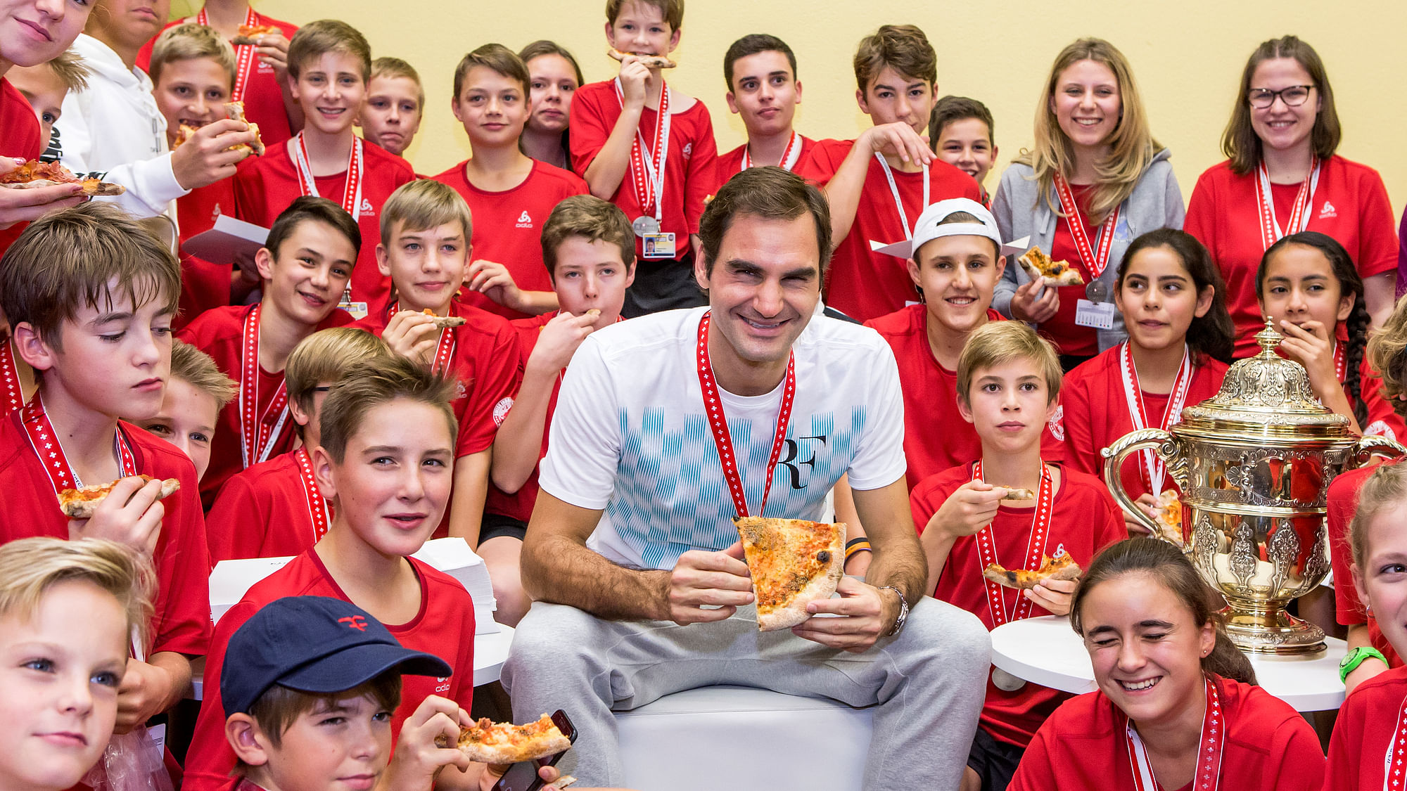 Switzerland’s Roger Federer eats pizza with ball kids after winning the final match against Argentina’s Juan Martin Del Potro at the Swiss Indoors tennis tournament at the St. Jakobshalle in Basel, Switzerland, on Sunday, October 29, 2017.&nbsp;