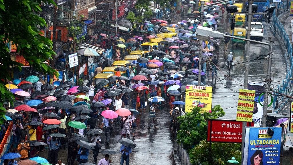  Commuters wait for buses and taxis during heavy rainfall in Kolkata on Monday.