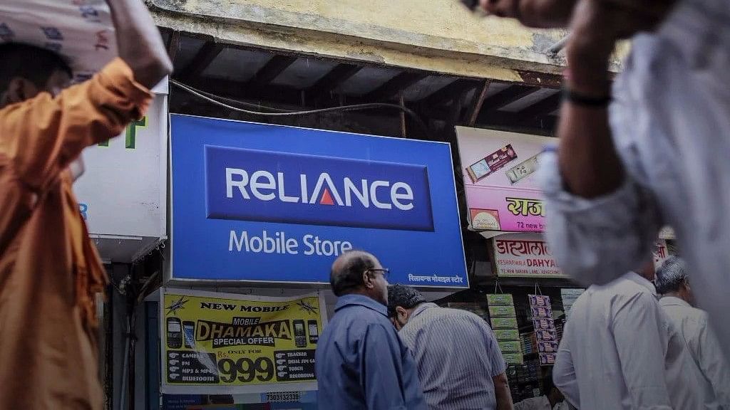 Pedestrians walk past a Reliance Communications Ltd. Mobile Store in Mumbai, India.&nbsp;