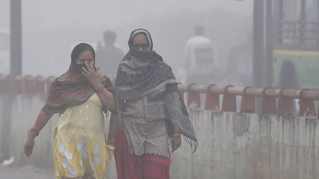 Women cover their face while walking through dense smog in New Delhi on Wednesday.&nbsp;