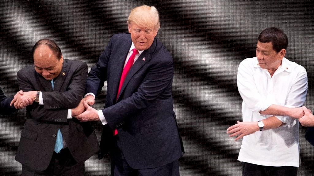 US President Donald Trump, center, reacts when he realizes he is incorrectly doing the “ASEAN-way handshake“.