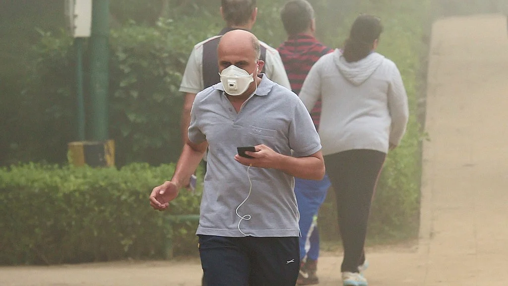 A man, wearing an anti-pollution mask, jogs through smog at Lodhi Garden in New Delhi.