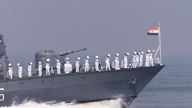 Indian Navy personnel salute from a naval ship.