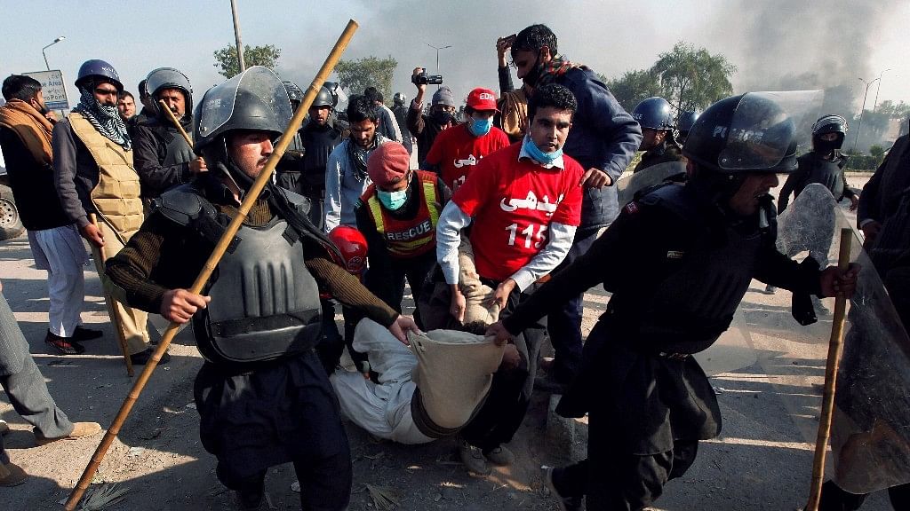 Pakistani police officers carry an injured protester during a clash in Islamabad, Pakistan, Saturday, 25 November. &nbsp;
