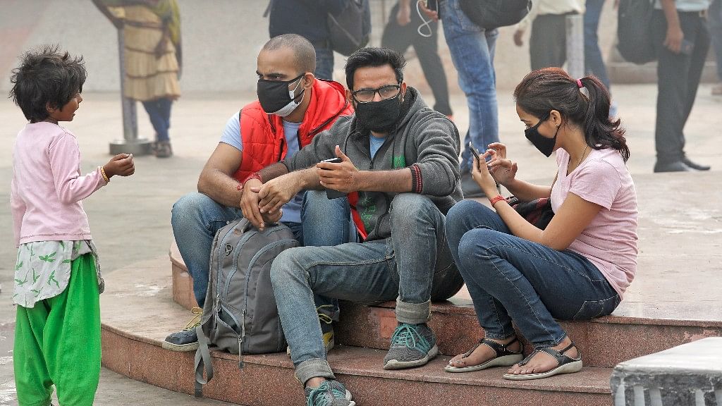 A girl begs for alms from a group of people wearing face masks to fight the pollution in New Delhi on 9 November.