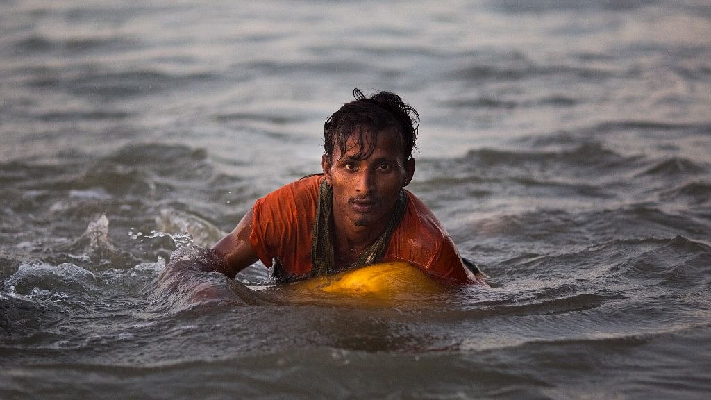 Rohingya Muslim Abdul Karim, 19, uses a yellow plastic oil container as a flotation device as he swims the Naf river while crossing the Myanmar-Bangladesh border in Shah Porir Dwip