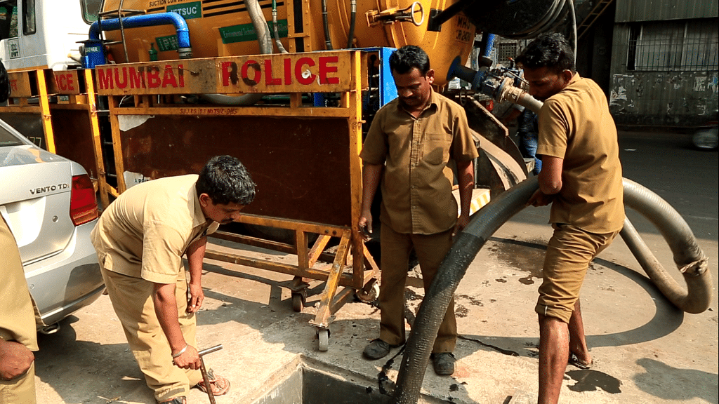 Gautam Shirke and other BMC workers attempt to clean up a clogged drain.