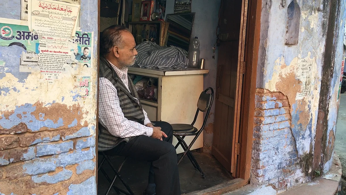 Imran Ahmad sits at tailor shop. 