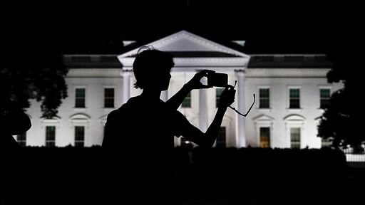 File photo: a tourist takes a photo from Pennsylvania Avenue of the illuminated White House in Washington.