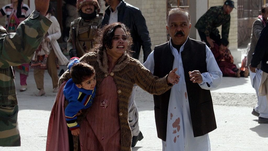 A man helps an injured woman and a child following an attack on a church in Quetta, Pakistan, Sunday.