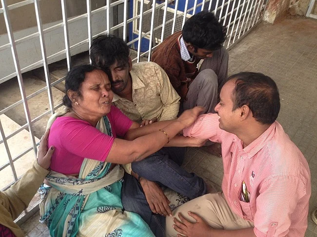 Kiran (dressed in a pink shirt), sat next to his mother, grieving; he just wept, not speaking a word even to his mother.