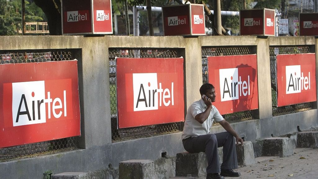A man talks on a mobile phone in front of advisements of Bharti Airtel in India.