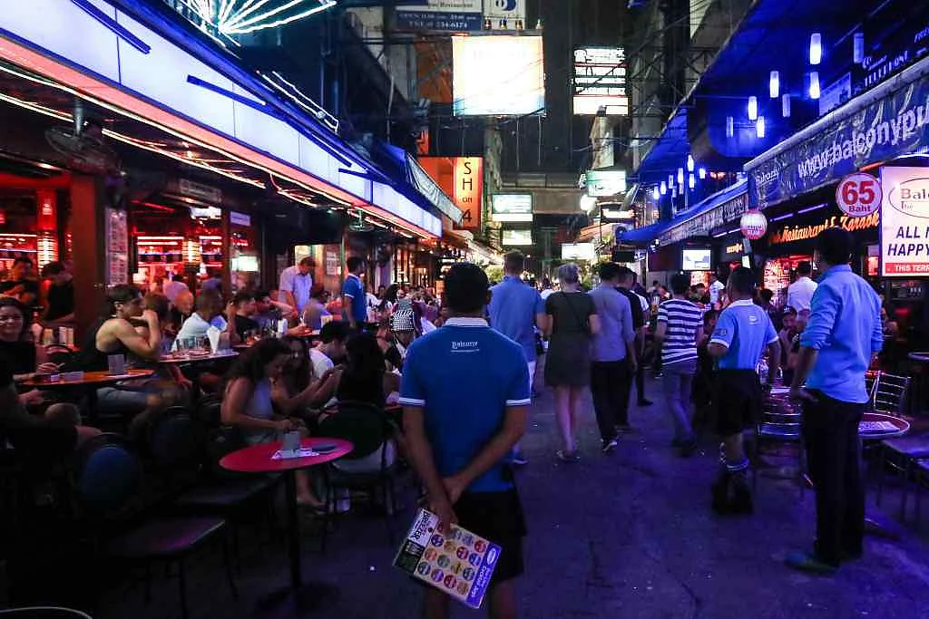 An employee, centre, stands between bars at night in the Silom area of Bangkok, Thailand.