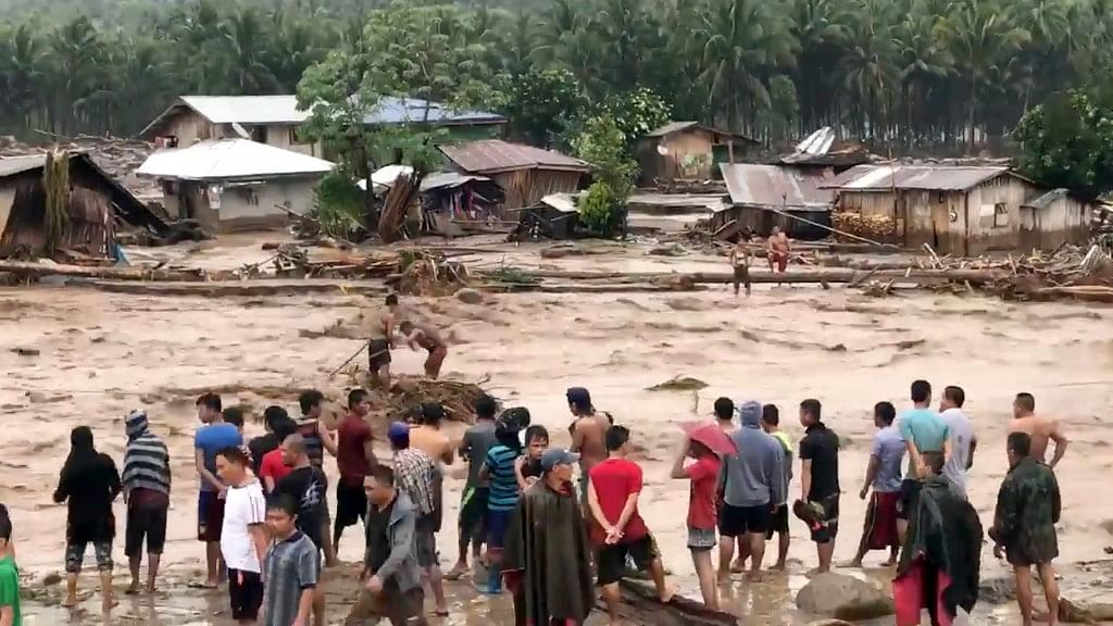 In this photo made from video by Aclimah Disumala on 22 December 2017, villagers carry cross raging flood waters in Lanao del Norte, Zamboanga Pennisula, southern Philippines.