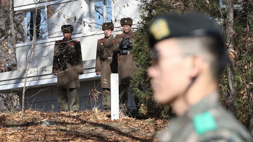 North Korean soldiers look at the South side as a South Korean stands guard near the spot where a North Korean soldier crossed the border on 13 November.
