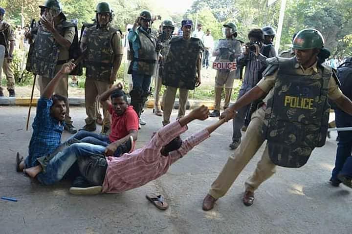 Police personnel dragging the students as they protest.