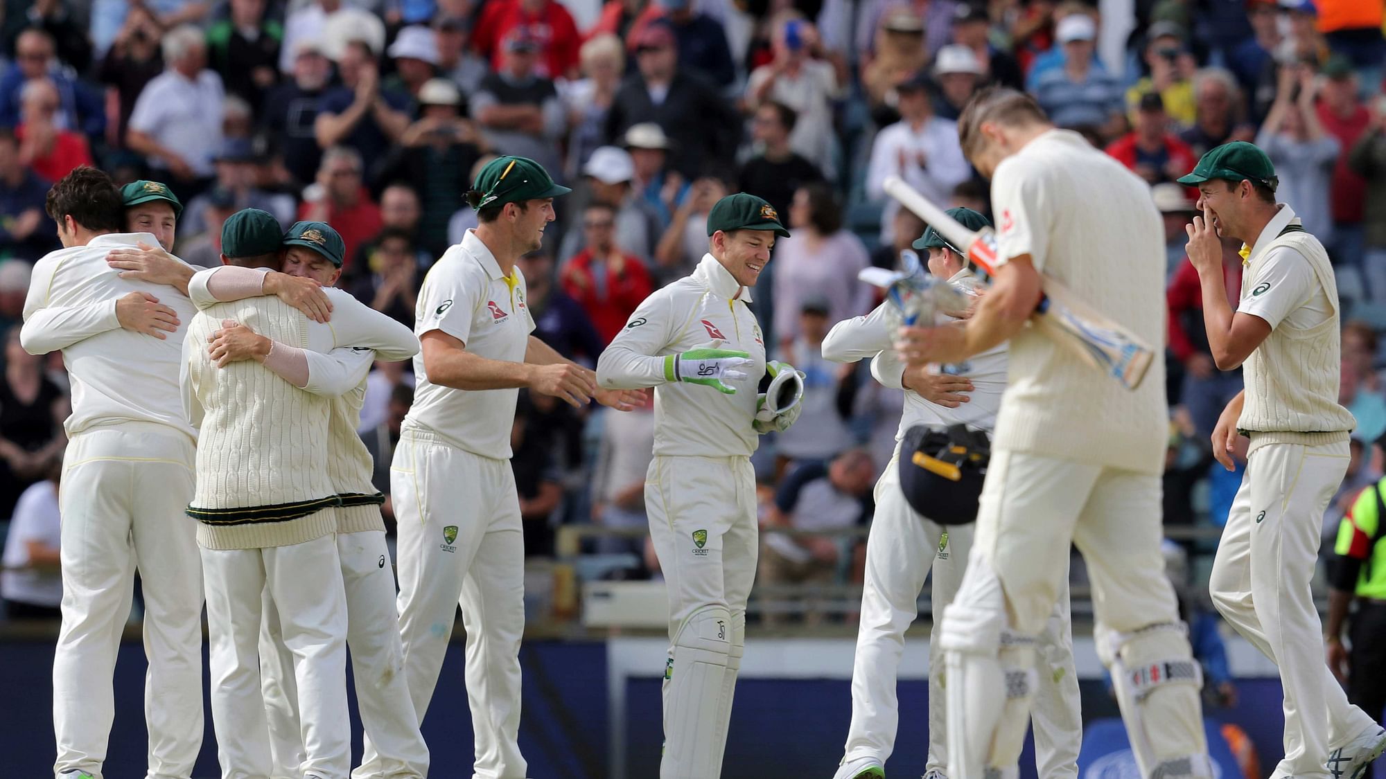Australian players celebrate winning their Ashes cricket test match as England’s James Anderson, second right, lowers his head in Perth